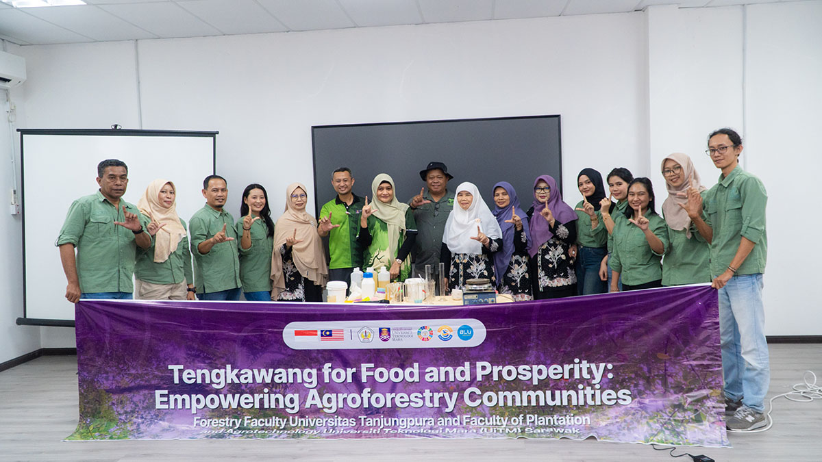 Kelompok peserta berfoto di belakang spanduk Tengkawang for Food and Prosperity dengan bahan serta perlengkapan demonstrasi di atas meja.