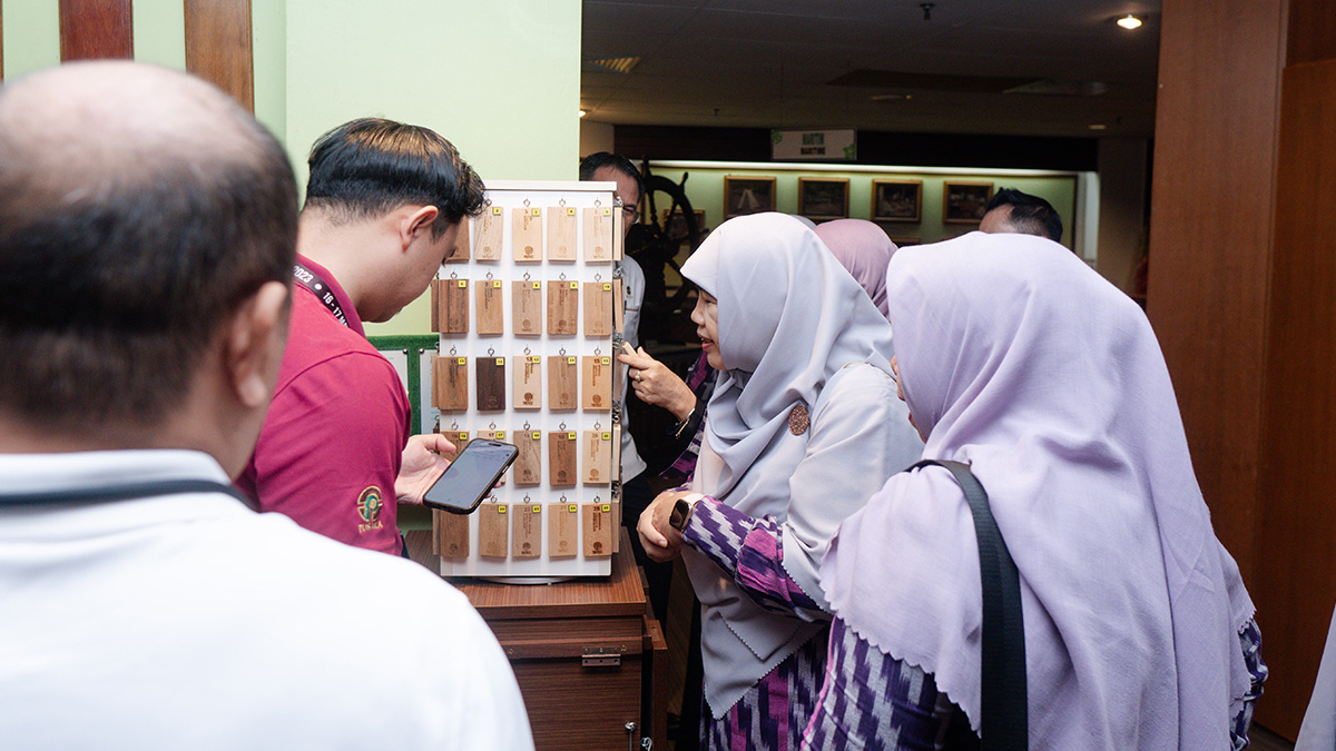 civitas akademika berdiskusi di ruang pamer museum dengan koleksi herbarium dan panel informasi kayu.
