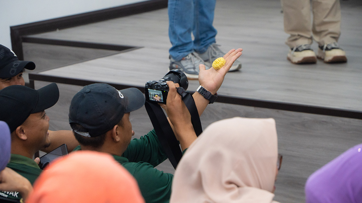 Contoh sabun berwarna kuning berbentuk bunga diperlihatkan di telapak tangan kepada peserta di ruang kegiatan.