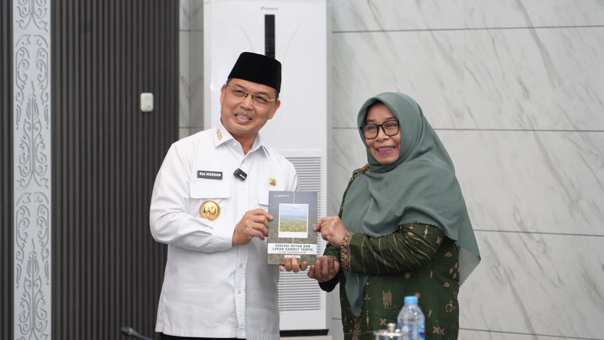 Prof. Dwi Astiani bersama Bapak Ria Norsan memegang buku Ekologi Hutan dan Lahan Gambut Tropis dalam rangkaian rapat karhutla.