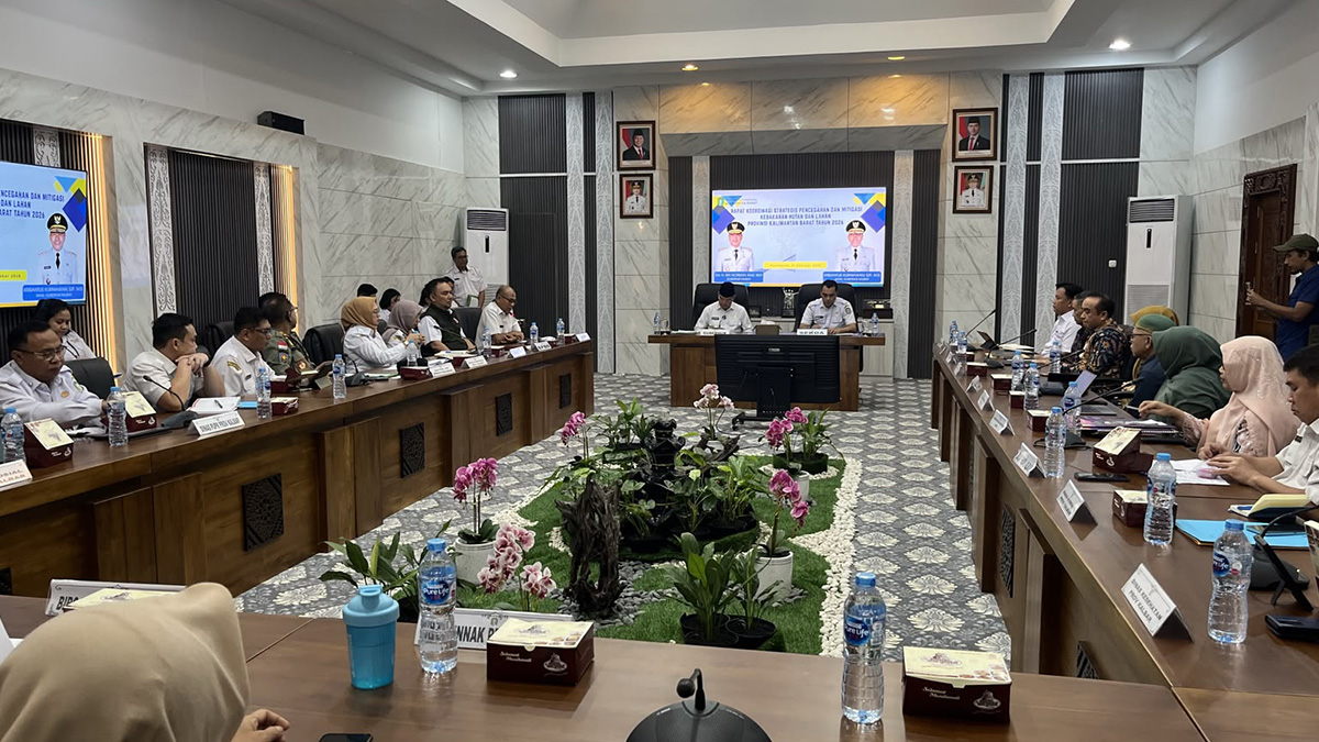 Peserta duduk mengelilingi meja rapat di Ruai Telabang dengan layar agenda koordinasi pencegahan dan mitigasi karhutla di bagian depan.